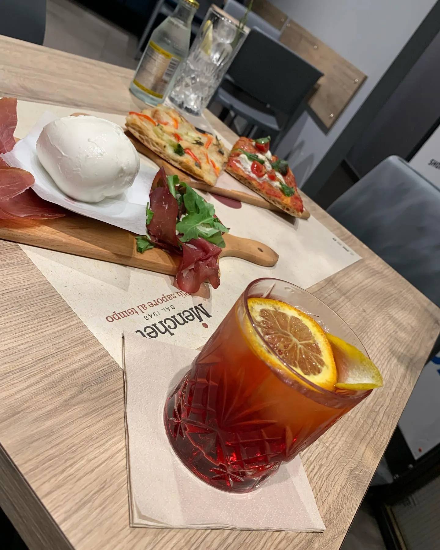 Tagliere con burrata, bresaola e pizza accompagnato da un cocktail rosso