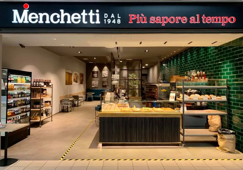 L'ingresso del Menchetti Point al Centro Gherlinda, con l'insegna «Più sapore al tempo» e le piastrelle verdi